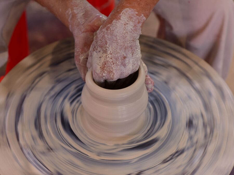 Hands throwing a pot on the wheel in the Nine Kilns studio